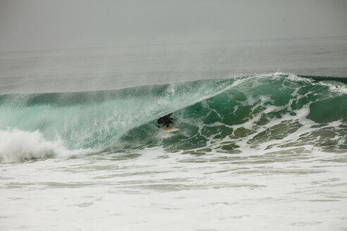 Ein männlicher Surfer navigiert beim Surfen in Westward in Malibu, Kalifornien, durch die Barrel. - AURF01147