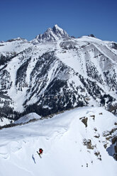 Ein Mann fährt auf einem steilen Hang mit dem Grand Teton im Hintergrund in der Nähe von Jackson Hole, Wyoming, Ski. - AURF01159