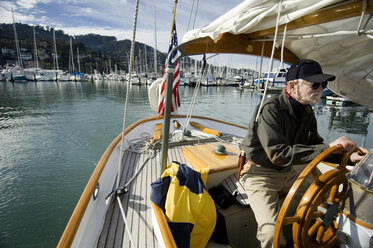 A man sails his yacht out of harbor. - AURF01177