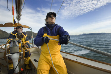 A man trims the sails on his yacht. - AURF01178
