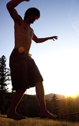 Ein professioneller Slackliner spielt auf einer Slackline in einem Feld bei Sonnenuntergang in den Blue Mountain von Missoula, Montana. - AURF01188