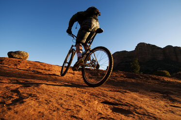 Ein Mann mittleren Alters fährt mit seinem Mountainbike durch die rote Felslandschaft von Sedona, AZ. - AURF01194