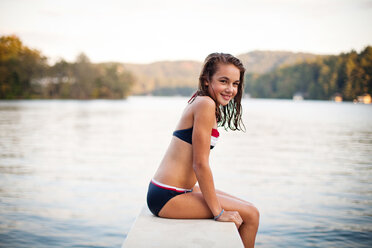 A portrait of a young girl on the edge of a diving board over a lake at dusk. - AURF01198