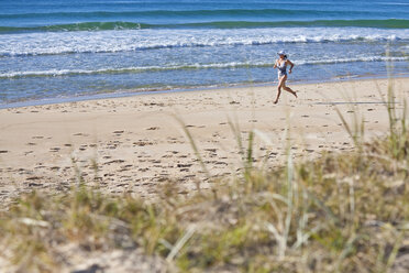 Eine Frau läuft über den weichen Sand am Sunshine Beach in Queensland, Australien. - AURF01221