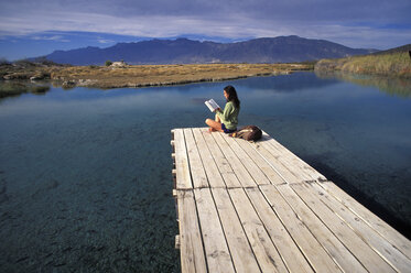 Eine Frau liest ein Buch am Wasser in Cuatro Cicnigas, Mexiko. - AURF01224