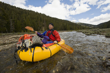 A young man paddles his small, inflatable raft at the source of the Salmon River in Idaho. - AURF01239