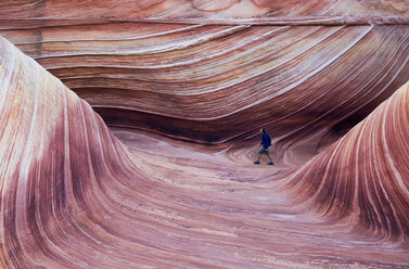 A young man hikes along a trail through The Wave in Vermillion Cliffs, Utah. - AURF01241