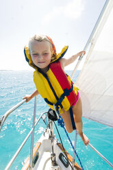 Ein junges Mädchen balanciert auf der Reling eines Segelboots auf den Bahamas. - AURF01246