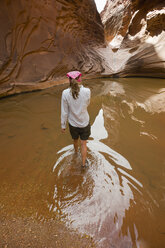 Eine junge Frau watet bei einer Wanderung durch den North Canyon des Colorado River durch ein Wasserbecken. - AURF01261