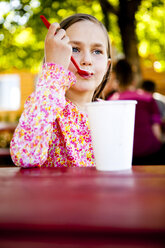 An eight year old girl, eats ice cream while sitting at red picnic table, Garden City, Utah. - AURF01292