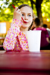 Ein achtjähriges Mädchen isst Eis, während es an einem roten Picknicktisch sitzt, Garden City, Utah. - AURF01292