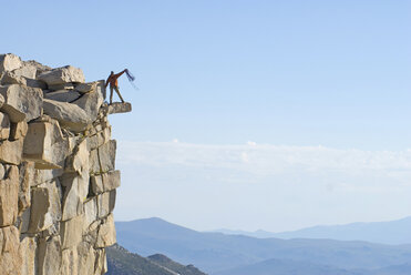Kletterer wickelt Seil auf dem Gipfel auf. - AURF01294