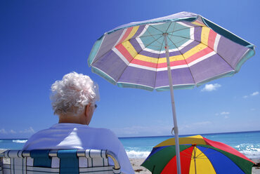 Ältere Frau sitzt im Schatten an einem Strand in Florida. - AURF01313
