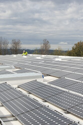 Techniker für grüne Energie justiert Fotovoltaikmodule auf einem Dach - AURF01327