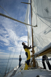 Man adjusts the rigging on his yacht. - AURF01369
