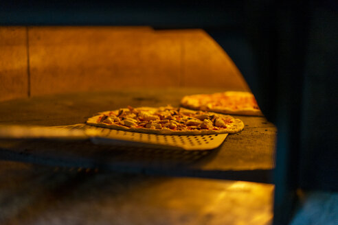 Eine Pizza mit Pizzaschieber in den Ofen schieben - AFVF01434