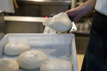 Nahaufnahme eines Pizzabäckers, der einen Haufen rohen Teig in eine Schachtel legt - AFVF01436