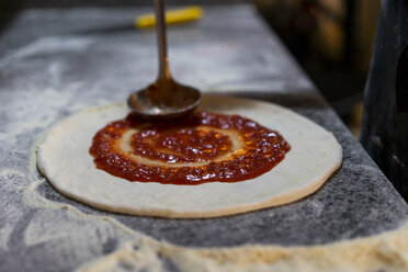 Zubereiten einer Pizza mit Tomatensauce in der Küche - AFVF01438