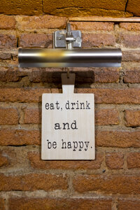 Tafel mit einem Spruch an einer Backsteinwand in einem Restaurant - AFVF01453
