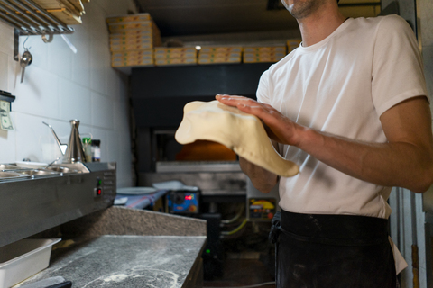 Nahaufnahme eines Pizzabäckers bei der Zubereitung von Pizzateig in der Küche, lizenzfreies Stockfoto