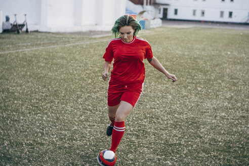 Junge Frau spielt Fußball auf einem Fußballplatz und läuft mit dem Ball - VPIF00509