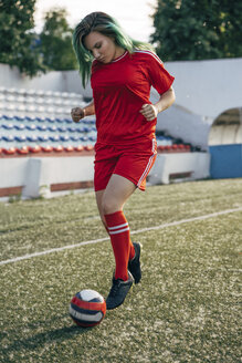 Junge Frau spielt Fußball auf einem Fußballplatz und dribbelt mit dem Ball - VPIF00515