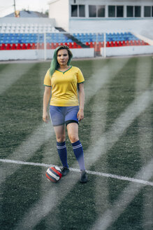 Junge Frau steht mit dem Ball auf dem Fußballplatz - VPIF00518