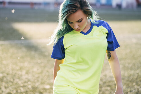 Porträt einer jungen Frau in einem Trikot auf einem Fußballplatz mit Blick nach unten - VPIF00522