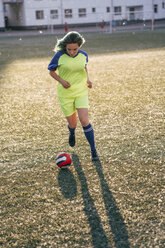 Young woman playing football on football ground running with the ball - VPIF00523