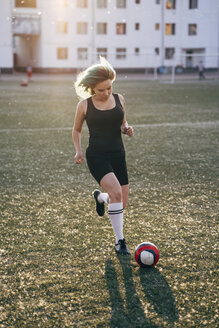 Junge Frau spielt Fußball auf einem Fußballplatz und läuft mit dem Ball - VPIF00526