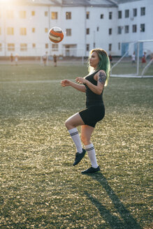 Junge Frau spielt Fußball auf einem Fußballplatz und balanciert den Ball - VPIF00527