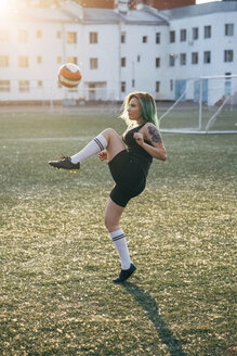 Junge Frau spielt Fußball auf einem Fußballplatz und balanciert den Ball - VPIF00528
