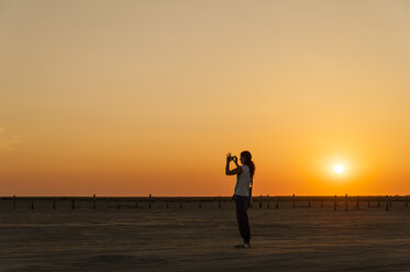 Deutschland, Schleswig-Holstein, Sankt Peter-Ording, Frau fotografiert am Strand bei Sonnenuntergang - UMF00833