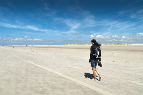 Deutschland, Schleswig-Holstein, Sankt Peter-Ording, Frau geht bei Ebbe am Strand spazieren, lizenzfreies Stockfoto