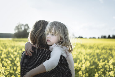 Porträt eines kleinen Mädchens auf den Armen ihrer Mutter in einem Rapsfeld - PSIF00006