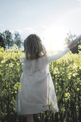 Back view of little girl walking on mother's hand in rape field - PSIF00014