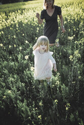 Portrait of little girl walking on rape field with her mother - PSIF00018