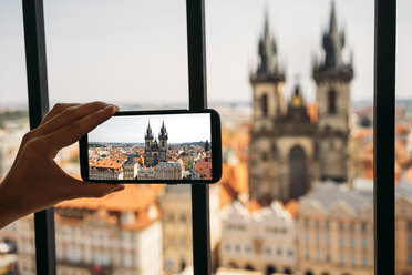 Czechia, Prague, woman taking photo of Church of Our Lady from old town hall with smartphone, partial view - GEMF02304