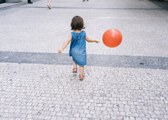 Rückansicht eines kleinen Mädchens mit rotem Luftballon auf dem Bürgersteig - GEMF02308
