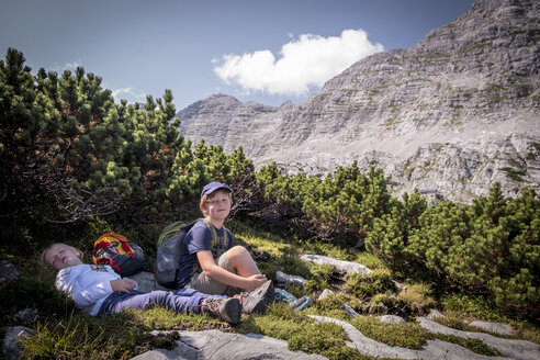 Österreich, Bundesland Salzburg, Loferer Steinberge, Bruder und Schwester ruhen sich bei einer Wanderung in den Bergen aus - HAMF00351