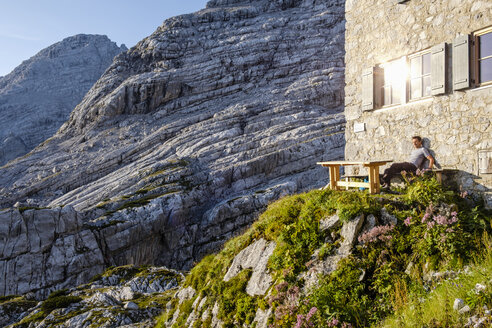 Österreich, Bundesland Salzburg, Loferer Steinberge, Wanderer sitzt auf einer Hütte und genießt die Aussicht - HAMF00356