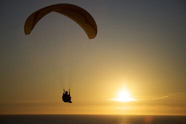 Ein Gleitschirmflieger reitet mit dem Wind bei Sonnenuntergang über dem Ozean in Kalifornien. - AURF01382