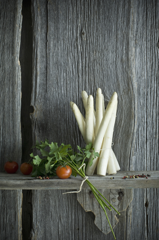 Bündel weißer Spargel, Tomate, Petersilie und gemischte Paprika auf Holz, lizenzfreies Stockfoto