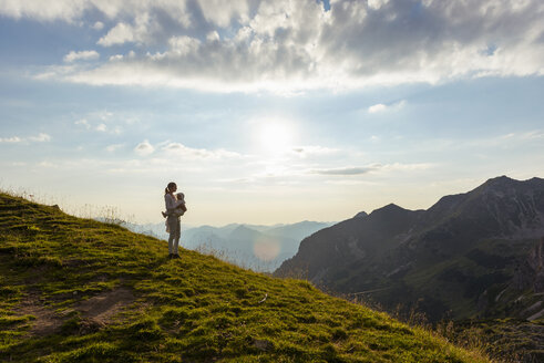 Deutschland, Bayern, Oberstdorf, Mutter und kleine Tochter bei einer Wanderung in den Bergen mit Blick auf den Sonnenuntergang - DIGF04982