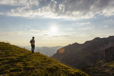 Deutschland, Bayern, Oberstdorf, Mann auf einer Wanderung in den Bergen mit Blick auf den Sonnenuntergang - DIGF04983