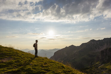 Deutschland, Bayern, Oberstdorf, Mann auf einer Wanderung in den Bergen mit Blick auf den Sonnenuntergang - DIGF04984