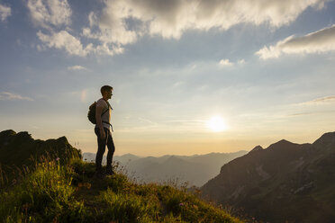 Germany, Bavaria, Oberstdorf, man on a hike in the mountains looking at view at sunset - DIGF04985