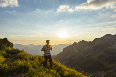 Deutschland, Bayern, Oberstdorf, Mann auf einer Wanderung in den Bergen bei Sonnenuntergang - DIGF04986