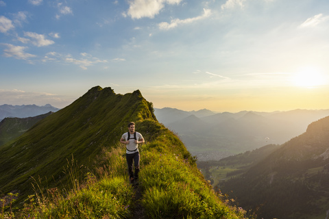 Germany, Bavaria, Oberstdorf, man hiking on a ridge in the mountains at sunset stock photo