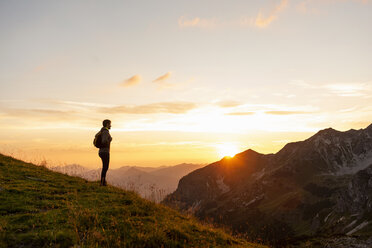 Germany, Bavaria, Oberstdorf, man on a hike in the mountains looking at view at sunset - DIGF04994